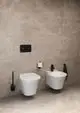Weißes Wand-Bidet und Toilette mit schwarzer Betätigungsplatte. Zubehör wie Toilettenpapierhalter und Bidetarmatur von Ideal Standard in Silk Black. Elegante, moderne Badezimmerausstattung.